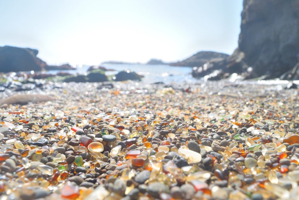 Rounded translucent pebbles of sea glass form a thin layer on the beach of a rocky cove in California. Photo by American photographer Carson Goldsmith.